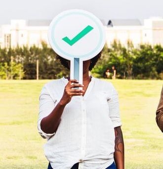 Woman holds up a sign with a green checkmark