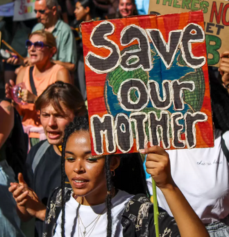 Protesters with a sign that reads "Save Our Mother" with planet Earth in the background