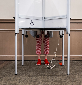 Voter with red shoes casting their vote at their polling place