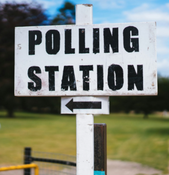 A white sign reads "POLLING STATION" in black text with an arrow pointing left.