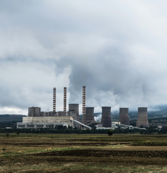 An image of a coal-fired power plant producing smoke over a landscape.